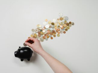 Person adding coins to a piggy bank for monthly budgeting and saving