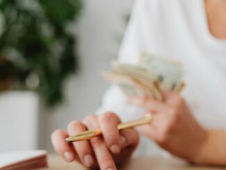 Budgeting and saving money – person using a calculator and counting cash
